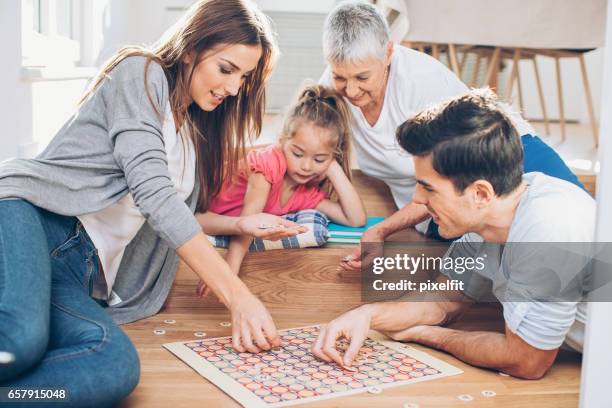 famille de plusieurs génération jouant un jeu de plateau - jeu de société photos et images de collection