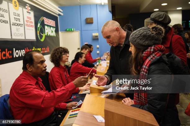 Workers serve customers behind a betting counter during a night of racing at Wimbledon Greyhound Stadium on March 25, 2017 in London, England....