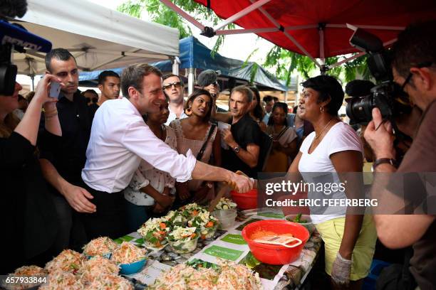 French presidential election candidate for the En Marche! movement Emmanuel Macron shakes hands with a food vendor during a visit to Le Chaudron...