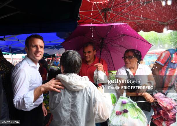 French presidential election candidate for the En Marche! movement Emmanuel Macron takes shelter from the rain during a visit to the Le Chaudron...