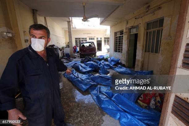 An Iraqi rescue worker gestures towards bodies wrapped in plastic in the Mosul al-Jadida area on March 26 following air strikes in which civilians...