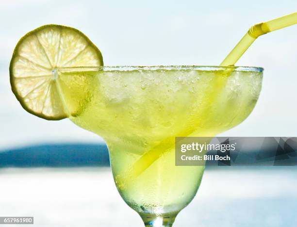 closeup of a margarita by the ocean with alime slice and a straw - cocktail glass salt stock pictures, royalty-free photos & images