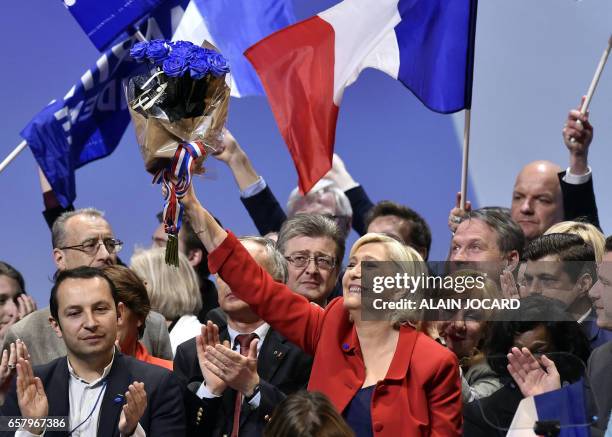 French presidential election candidate for the far-right Front National party Marine Le Pen brandishes blue roses after speaking during a campaign...