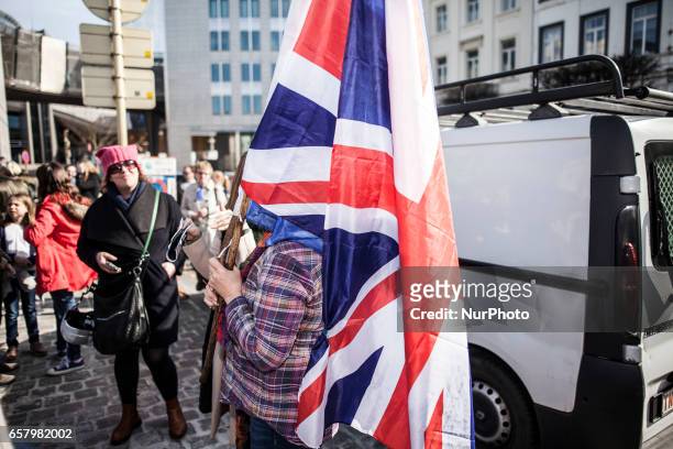 Illustration picture shows a woman holding a British flag and a flag of the European Union. In front of the European Parliament people gathered to...
