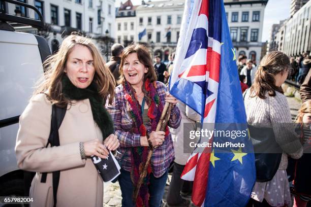 Illustration picture shows a woman holding a British flag and a flag of the European Union. In front of the European Parliament people gathered to...