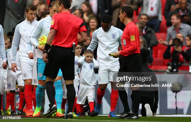 Mascot Bradley Lowery covers his ears as he walks out with Jermain Defoe of England during the FIFA 2018 World Cup Qualifier between England and...