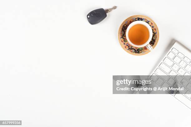 high angle view of office desk table with car key, green tea and computer keyboard, white background copy space - car keys table stock pictures, royalty-free photos & images