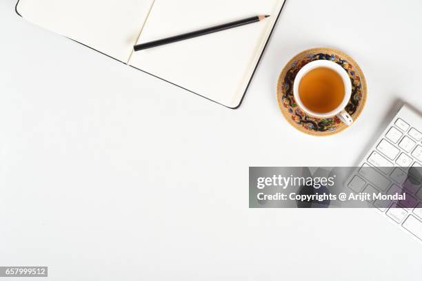 clean white office desk of a professional with writing notebook, pencil, black tea and computer keyboard - agenda meeting stock pictures, royalty-free photos & images