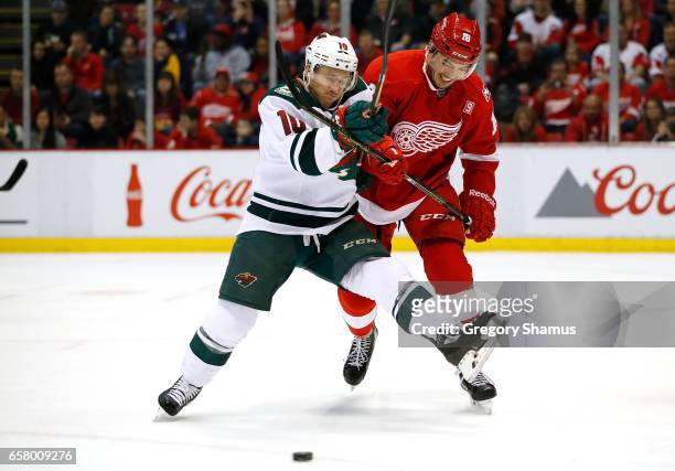Jordan Schroeder of the Minnesota Wild battles for the puck with Robbie Russo of the Detroit Red Wings during the first period at Joe Louis Arena on...