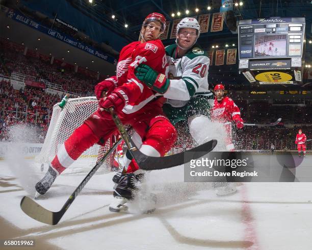 Danny DeKeyser of the Detroit Red Wings battles for position with Ryan Suter of the Minnesota Wild during an NHL game at Joe Louis Arena on March 26,...
