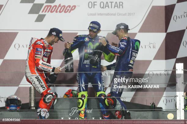 Champion Movistar Yamaha MotoGP's racers Maverick Vinales , teammate Valentino Rossi , and Ducati Team's Italian racer Andrea Dovizioso celebrate on...
