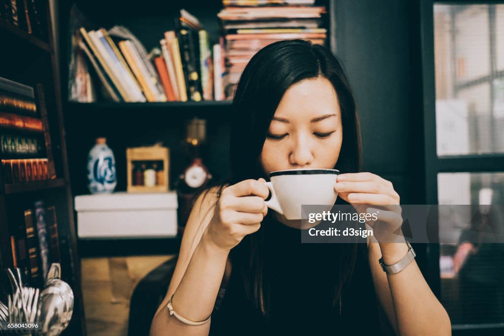 Young Asian lady having a relaxing coffee time in cafe