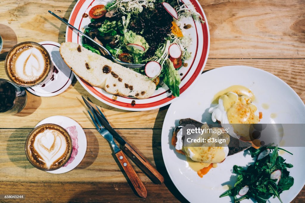 Brunch for two people with egg benedict and mixed greens and coffee freshly served on the table