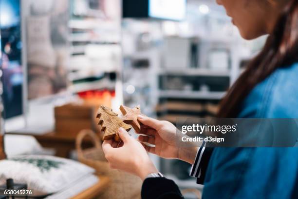 woman shopping for wooden christmas ornaments in shop - christmas decorations in store stock pictures, royalty-free photos & images