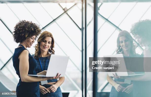 zwei geschäftsfrauen, die im büro arbeiten und laptop verwenden - hr technology stock-fotos und bilder