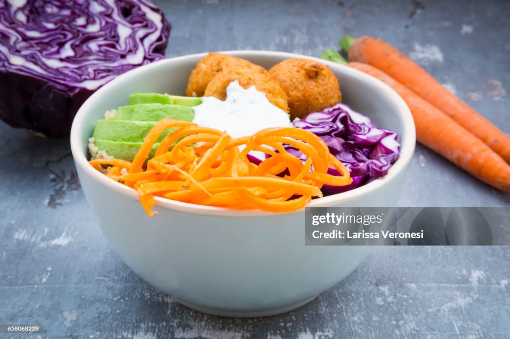 Quinoa lunch bowl with sweet potato falafel, carrots, red cabbage, avocado and yoghurt sauce