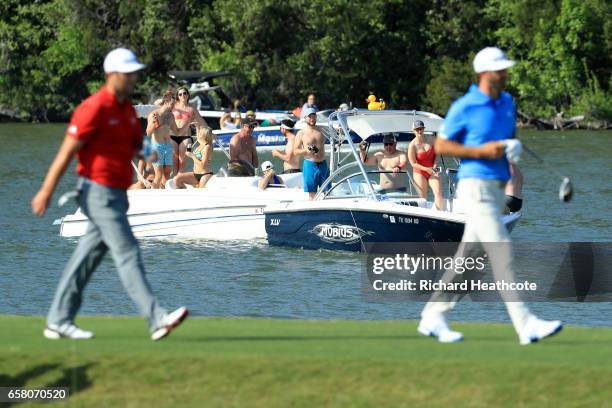 Jon Rahm of Spain and Dustin Johnson walk on the 14th hole while fans watch from a boat during the final match of the World Golf Championships-Dell...