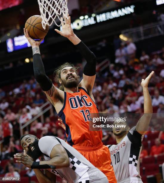 Steven Adams of the Oklahoma City Thunder goes up between James Harden of the Houston Rockets and Eric Gordon for a layup at Toyota Center on March...
