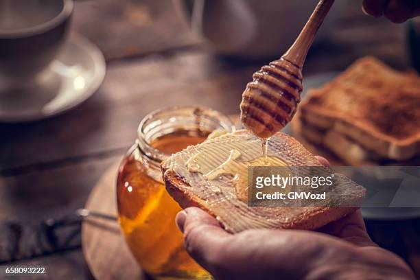 toast met honing voor het ontbijt - honinglepel stockfoto's en -beelden