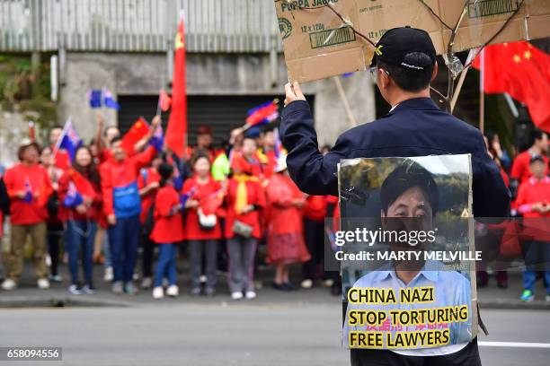 Protester holds a sign opposite Chinese supporters outside Premier House after China's Premier Li Keqiang left a press conference in Wellington on...