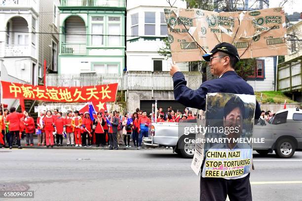 Protester holds a sign opposite Chinese supporters outside Premier House after China's Premier Li Keqiang left a press conference in Wellington on...