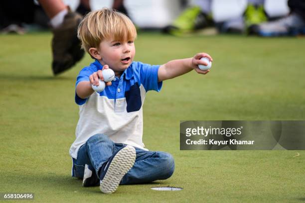 Tatum Johnson, son of Paulina Gretzky and Dustin Johnson plays with golf balls on the 18th hole green after his dad's 1-up victory during the...