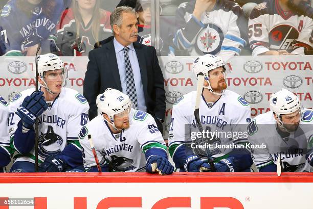 Head Coach Willie Desjardins, Joseph LaBate, Henrik Sedin, Daniel Sedin and Michael Chaput of the Vancouver Canucks look on from the bench during...