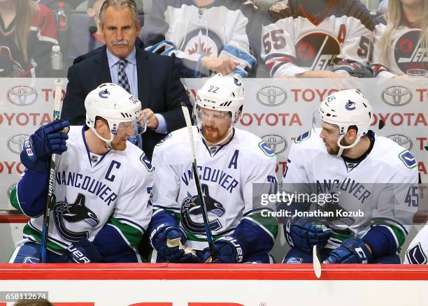 Henrik Sedin, Daniel Sedin and Michael Chaput of the Vancouver Canucks discuss strategy on the bench during second period action against the Winnipeg...