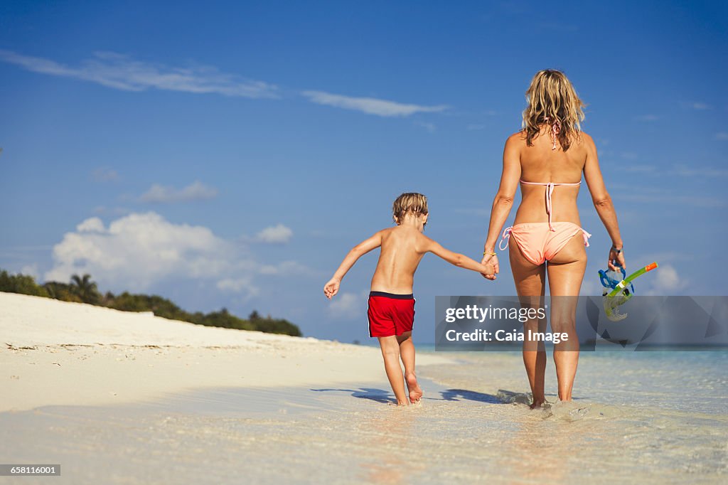 Mother and son walking on sunny tropical beach