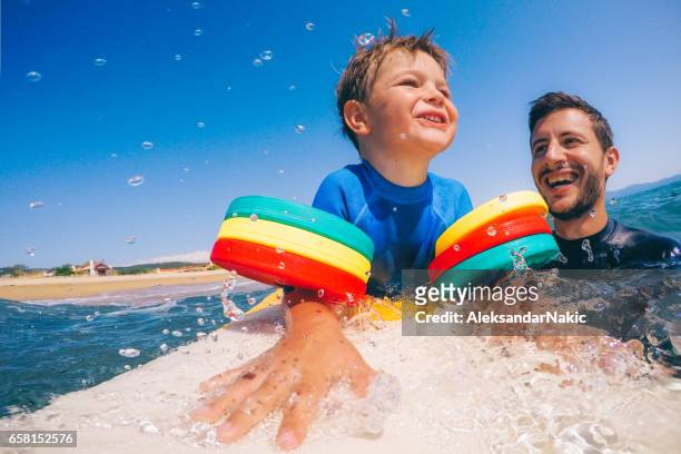 little boy on surfboard - candid beach stock pictures, royalty-free photos & images