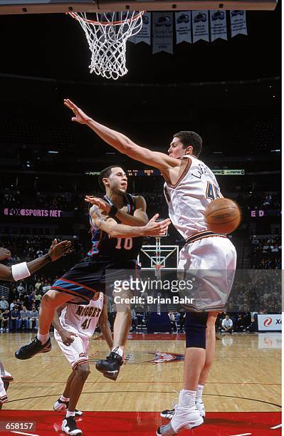 Mike Bibby of the Vancouver Grizzlies jumps as he passes the ball around Raef La Frentz of the Denver Nuggets at the Pepsi Center in Denver,...