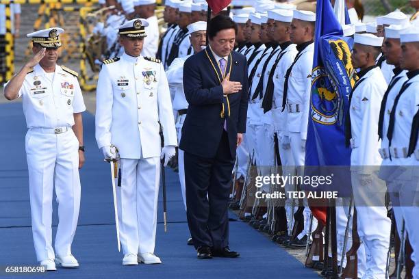 Japanese Deputy Defence Minister Kenji Wakamiya bows while Philippine's navy chief Vice Admiral Ronald Mercado salutes at a troop review at a naval...