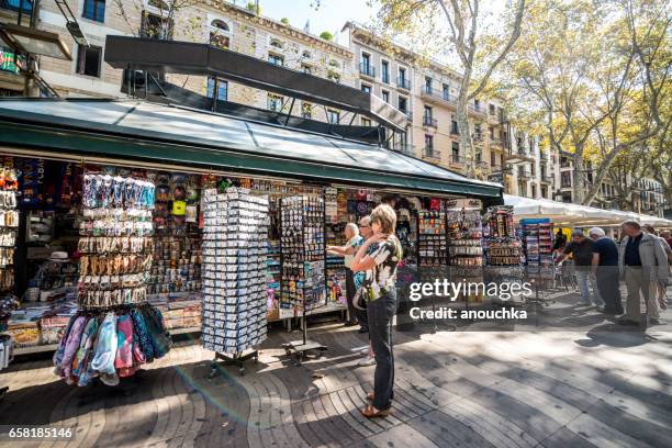 kiosk mit geschenken mit touristen in barcelona, spanien - barcelona postcard stock-fotos und bilder