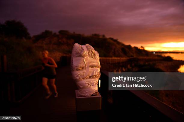 The sun sets on a piece of public art wrapped in bubble wrap for protection along a walkway at Kissing Point in preparation for Cyclone Debbie on...