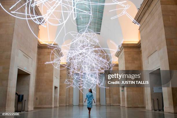 Gallery assistant poses for photographers during a photocall to promote Welsh artist's Cerith Wyn Evans new light installation entitled "Forms in...