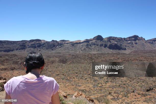 woman from behind, looking down and mountain landscape in teide national park, tenere, spain - tenere stock-fotos und bilder