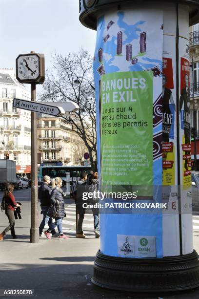 Poster denouncing tax evasion has been sticked on an advertising column by militants of international NGO OXFAM, on March 27, 2017 in Paris. / AFP...