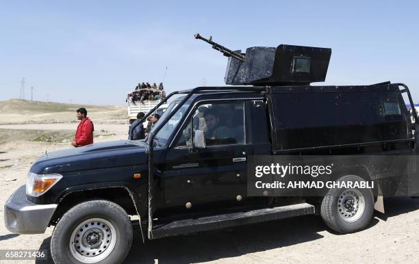 Iraqi security forces vehicles are seen as they drive alone pick up trucks carrying displaced Iraqis, who fled their homes in the Old City in western...
