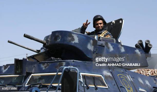 An Iraqi security forces member flashes the sign for victory as he secures displaced Iraqis, who fled their homes in the Old City in western Mosul...