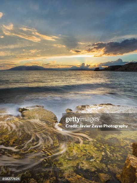 rocky cliff against seascape during sunset - olas rompientes stock pictures, royalty-free photos & images