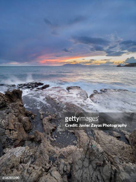 rocky cliff against seascape during sunset - mojado stock-fotos und bilder