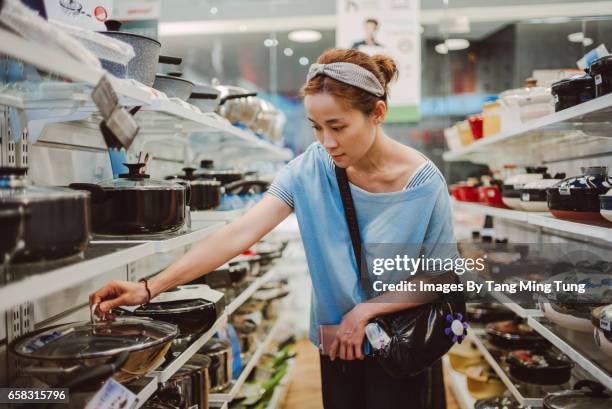 pretty young lady choosing kitchenware in a department store. - it department stock-fotos und bilder