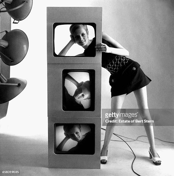 British fashion model Twiggy looking through a cut out above television screens showing images of her face, in a shoot for Vogue Magazine, Paris,...