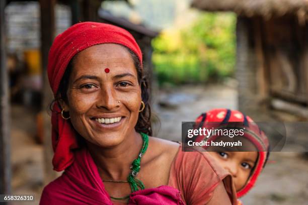 nepali woman carrying her baby near annapurna range - nepali mother stock pictures, royalty-free photos & images