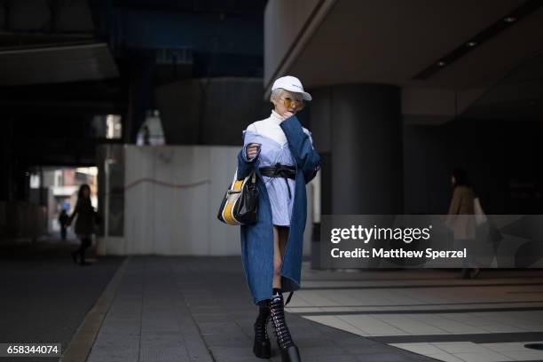 Guest is seen on the street wearing a white baseball cap with blue denim coat and light blue top with white sweater and black combat platform boots...