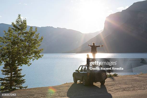 woman extends arms on car roof while man relaxes - arms outstretched bildbanksfoton och bilder