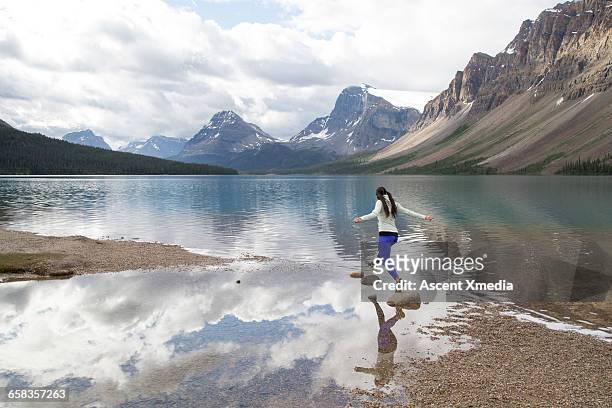 young woman hops between rocks, mountain lake - 踏み石 ストックフォトと画像