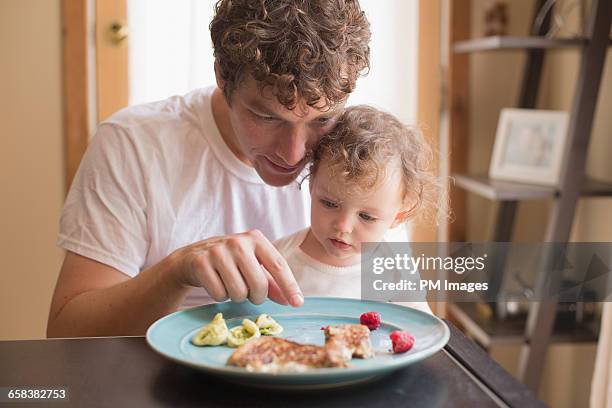 father and baby daughter eating - leanincollection father stock pictures, royalty-free photos & images