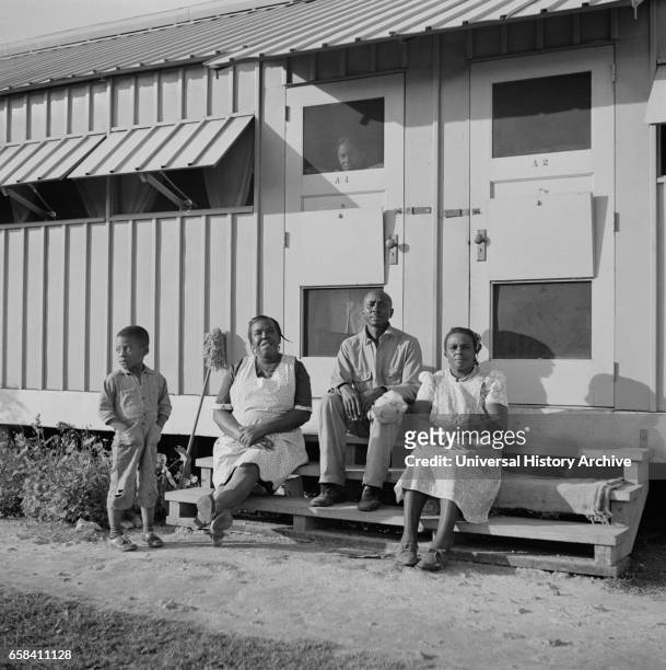 Family of Migratory Laborers Sitting in front of their Metal Shelter, Okeechobee Migratory Labor Camp, Belle Glade, Florida, USA, Marion Post Wolcott...
