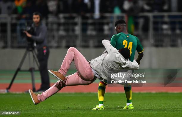 Pitch invader tackles Lamine Gassama of Senegal during the International Friendly match between the Ivory Coast and Senegal at the Stade Charlety on...